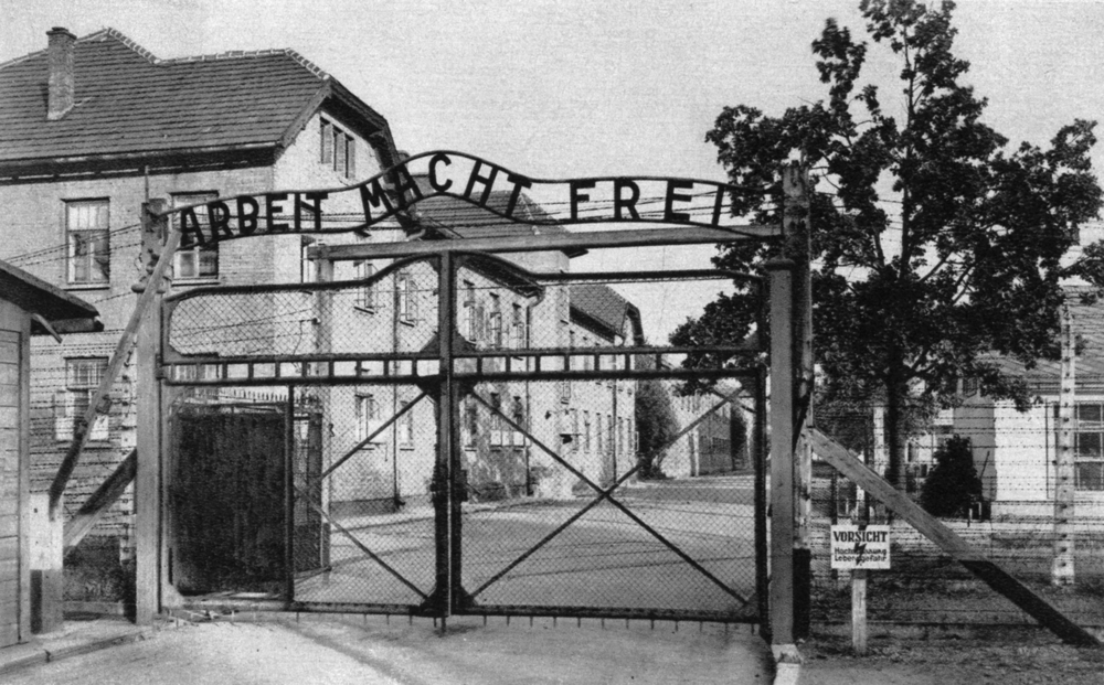 Portail de l’entrée principale d’Auschwitz-I , le “camp souche” : « Arbeit macht frei » (le travail rend libre). Carte postale. Collection mémoire Vive. Photo : Stanislas Mucha.