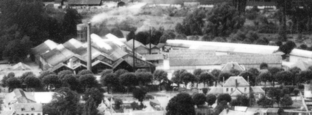 Le bâtiment au premier plan à droite est celui de l’école maternelle. De l’autre côté de l’avenue, matérialisée par le rideau de platanes, on devine le toit de l’école élémentaire avec la verrerie à l’arrière-plan. Carte postale non datée. Collection Mémoire Vive.