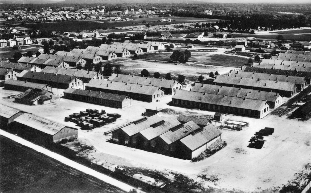 La caserne de Royallieu en 1957 ; au deuxième plan, alignés transversalement, les six grands bâtiments du quartier C. Isolés par une clôture de barbelés, ils ont constitué le “camp juif” du 13 décembre 1941 au 6 juillet 1942. Ensuite, ils ont servi au regroupement des détenus pour le prochain convoi en partance. L’enceinte et les miradors du camp ont disparu (les deux hangars en bas à gauche n’existaient pas). Carte postale. Coll. Mémoire Vive.