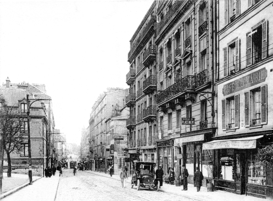 Saint-Mandé, l’avenue de la République, dans les années 1900. La façade du n° 38 apparaît au centre, derrière et au-dessus de l’automobile en stationnement. Carte postale, collection Mémoire Vive.